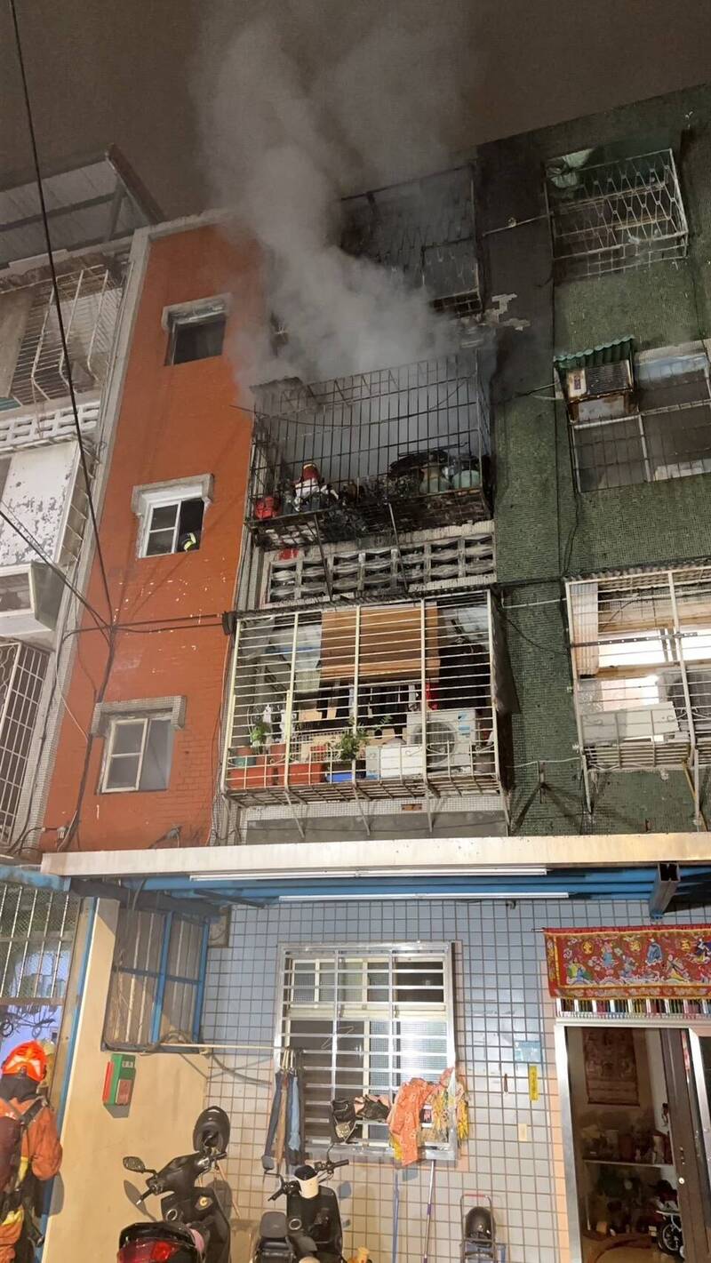 新北市板桥一处民宅今天凌晨失火，近八旬女住户疑听到住警器警报，及时逃出，消防搜救小组随后架梯救出受困火场男子，奇迹仅受轻伤，起火原因仍待调查厘清。（记者吴仁捷翻摄）