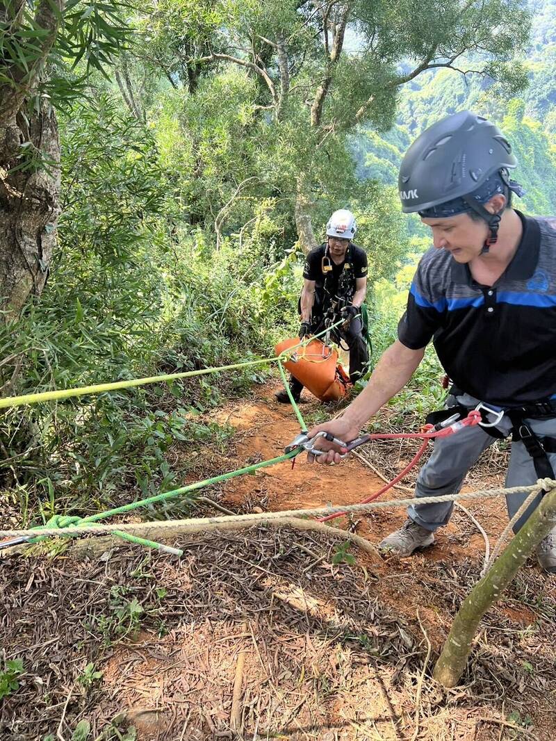 彰化夫妻档爬山，惟妻子不慎坠落50公尺边坡伤重身亡，搜救人员在接近垂直的陡坡架绳将人拉上步道。（记者刘滨铨翻摄）